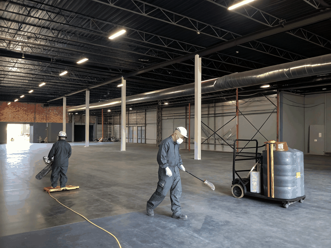 TriServe technicians positioning commercial HEPA air filtration equipment in a multi-story building hallway
